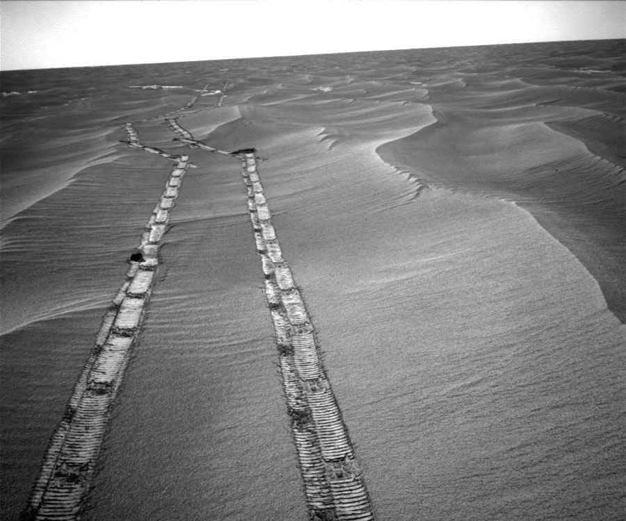 Über eine Dünenlandschaft verlaufen die Spuren eines Rovers. Sie zeigen Anzeichen für Schäden an den Rädern.