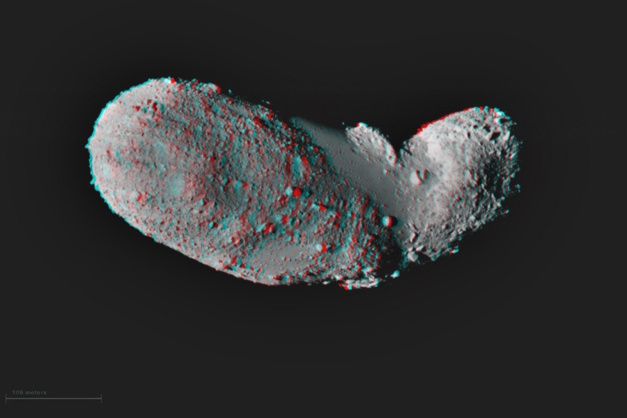 Das ro-blaue Bild zeigt den Asteroiden Itokawa, er ist von Geröll übersät und hat eine längliche, leicht gewinkelte Form.