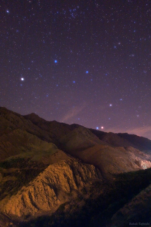 Der rote Mars und der blaue Regulus leuchten auf dieser Berglandschaft knapp über dem Horizont. Links neben dem Sternbild Löwe leuchtet der ebenfalls helle Planet Saturn.