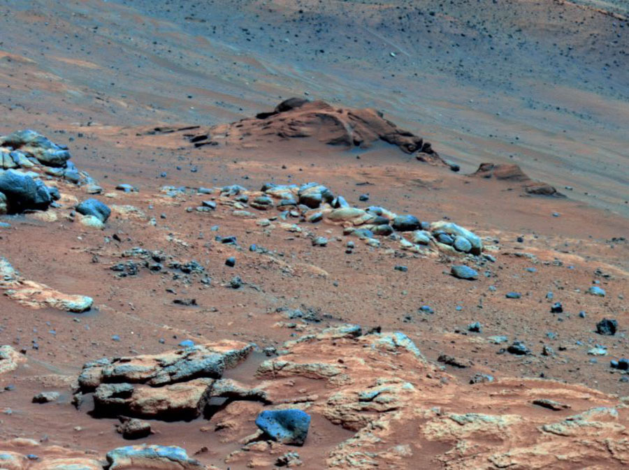 In der Marslandschaft sind manche Steine in blauen Falschfarben dargestellt. Wenn man mit der Maus übers Bild fährt, wird eine beschriftete Bildversion gezeigt. Erklärung im Text.