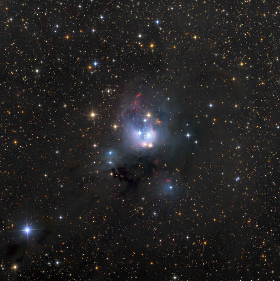 Mitten in einem Sternenfeld leuchtet ein blauer Nebel mit einigen hellen Flecken. Beschreibung im Text.