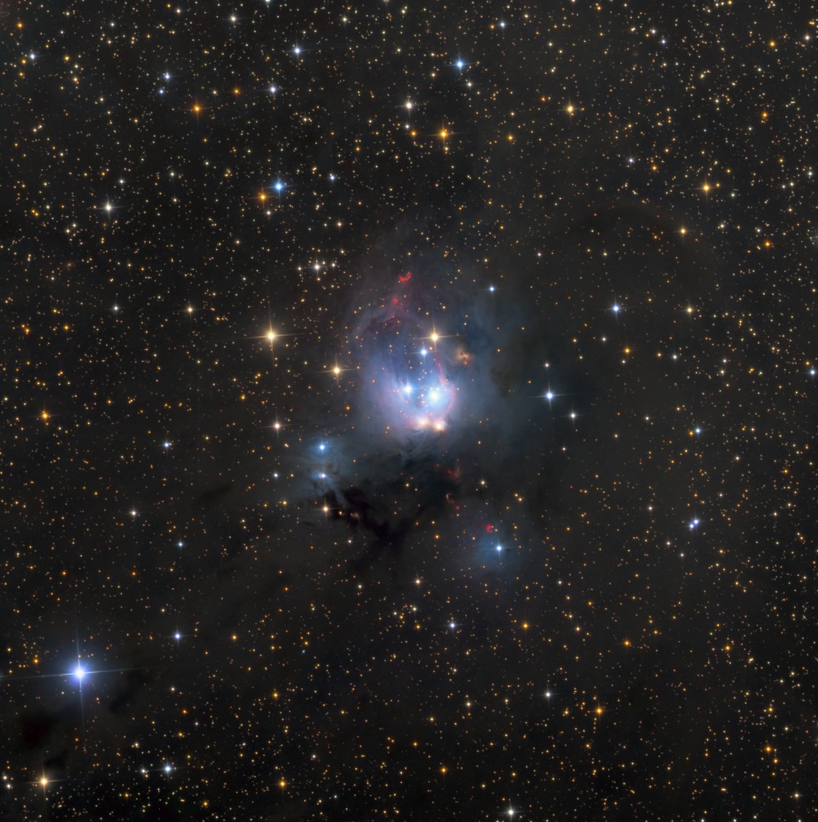 Mitten in einem Sternenfeld leuchtet ein blauer Nebel mit einigen hellen Flecken. Beschreibung im Text.