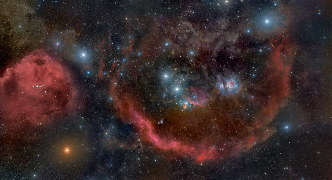 Waagrecht liegt das Sternbild Orion und seine nebelreiche Umgebung im Bild. Rundherum verläuft die Barnard-Schleife.