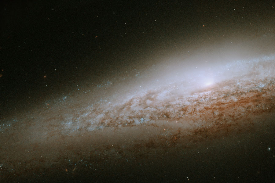 Wir blicken schräg auf eine Spiralgalaxie, die rechts abgeschnitten ist. Sie besitzt zahlreiche Staubwolken.