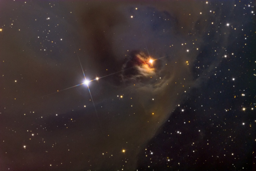 Ein brauner Nebel breitet sich über die linke Bildhälfte aus, in der Mitte leuchtet links ein Stern, rehts ist eine rötliche Höhlung mit einem zweiten Stern.