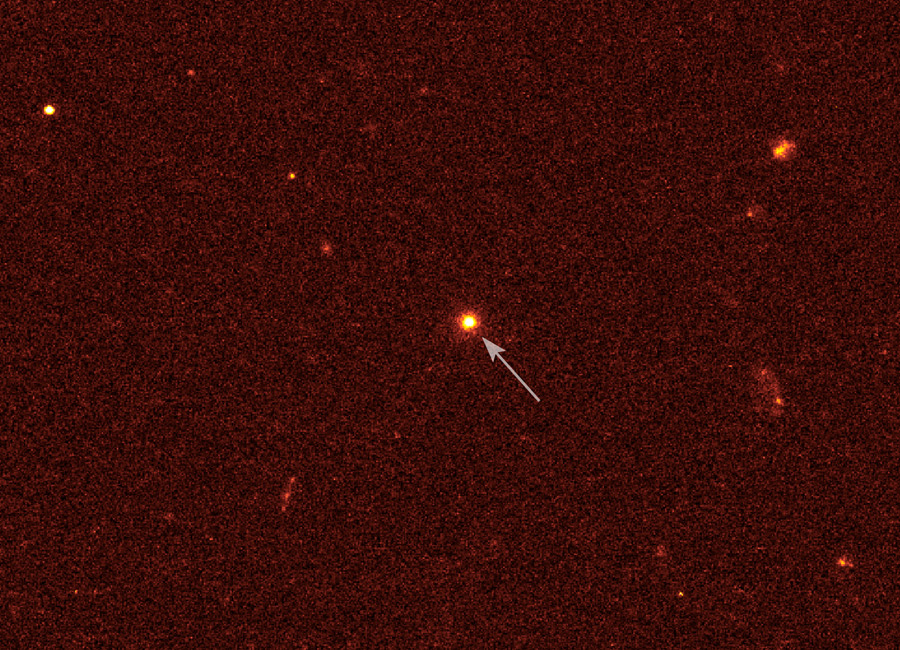 Mitten im Bild leuchtet ein heller Stern mit rotem Rand, der mit einem Pfeil markiert ist.