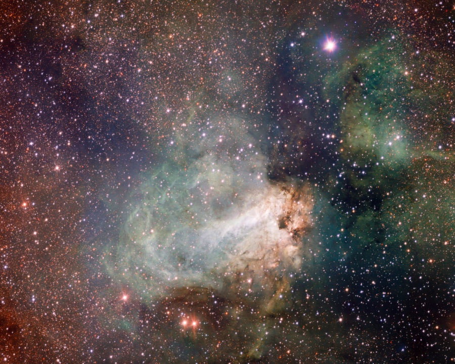 Mitten im Bild leuchtet ein weiß-grünlicher Nebel, der von rechts aus einer Höhle aus dunklem Staub zu strömen scheint. Im Bild sind kleine Sterne verteilt.