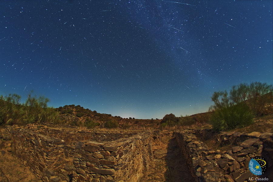 Hinter den Ruinen von Capote in der spanischen Provinz Badajoz strömen die Meteore der Draconiden vom Himmel.