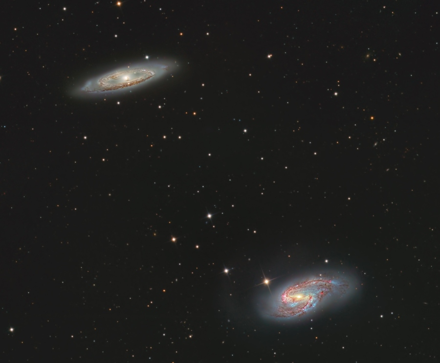 Die hellen Spiralgalaxien im Bild gehören zum Leo-Triplett im Sternbild Löwe, sie leuchten links oben und rechts unten. Beide besitzen ausgeprägte Spiralarme und dichte Staubbahnen.