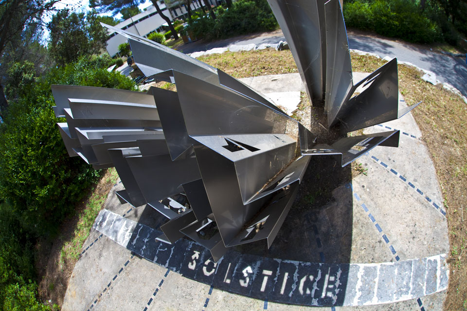 Das seltsam geformte Metallgebilde im Bild ist eine Sonnenuhr. Nur zu Sonnenwende schreibt die Sonne durch die Lücken das Wort SOLSTICE, und nur bei Tag- und Nachtgleiche das Wort EQUINOXE.