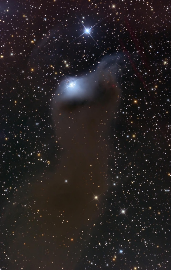 Vor einem sternklaren Hintergrund ragt eine verschwommene graue Wolke auf, die links oben von einem Stern blau beleuchtet wird.