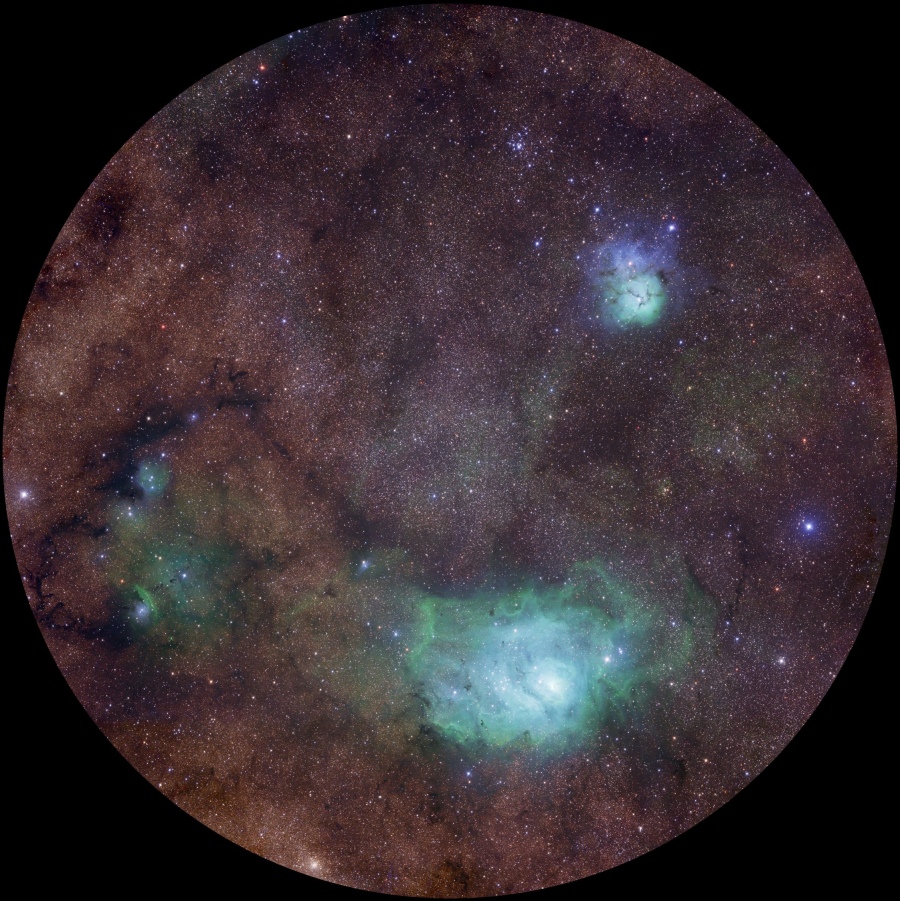 Eingebettet in dunkelrote Staubwolken sind drei bekannte Nebel in grünen Farbtönen, die man eigentlich rot leuchtend kennt: der Lagunennebel, der Trifidnebel und NGC 6559 im Sternbild Schütze.