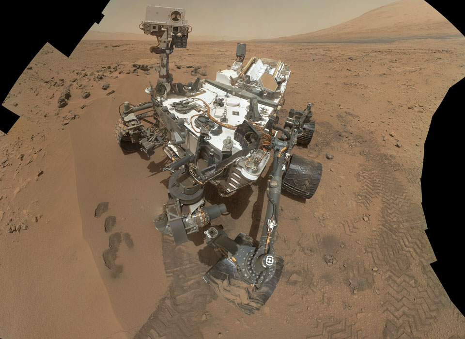 Das Mosaik zeigt einen Marsrover, der seine Spuren im Marsstaub hinterlassen hat. Durch einen Kunstgriff wurde der Arm, mit dem die Einzelbilder aufgenommen wurden, digital entfernt.