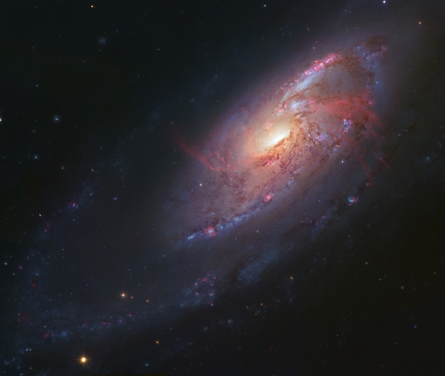 Die Spiralgalaxie M106 oder NGC 4258 im Sternbild Jagdhunde breitet im Bild ihre Spiralarme aus. Neben blauen und rötlichen Sternbildungsstätten gibt es auch Hinweise auf Materieströme, die ein Schwarzes Loch speisen.