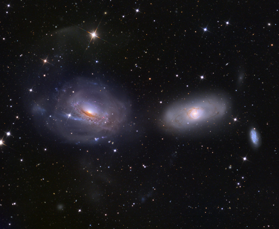 Mitten im Bild leuchten zwei schräge Galaxien, die an Augen erinnern. Ihre Spiralarme wurden durch Gezeiten bei engen Begegnungen verzerrt.