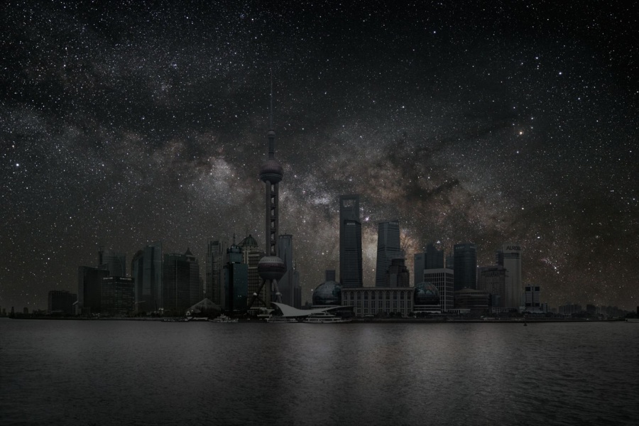 Die Megacity Schanghai in China ist hier dunkel, darüber steigt die Milchstraße mit ihren Dunkelwolken auf.