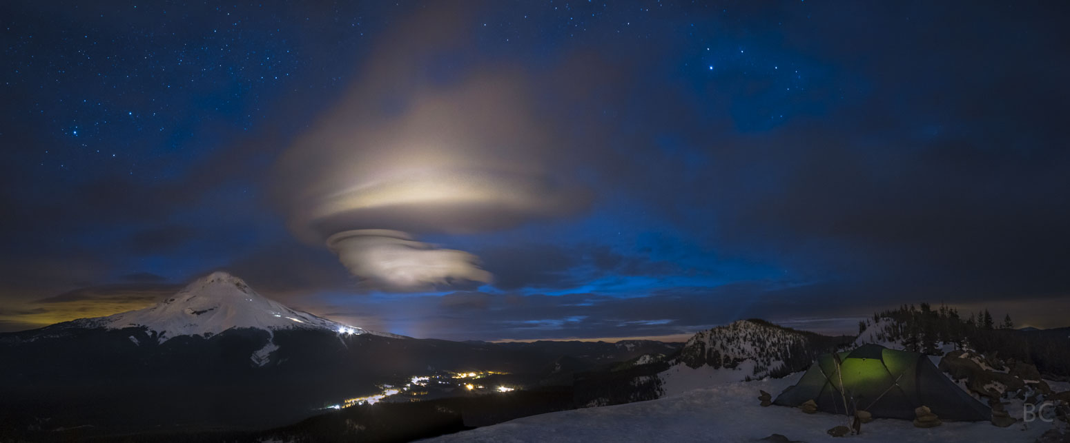 Über dem Mount Hood im US-amerikanischen Bundesstaat Oregon schwebt eine Lenticularis. Der Berg ist schneebedeckt, im Tal sind Lichter.