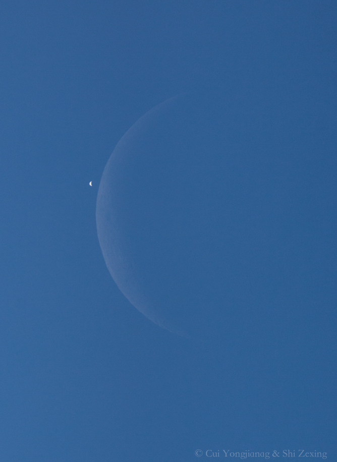 Am blauen Tageshimmel ist links neben der blassen Mondsichel die gleißende Sichel der Venus zu sehen, kurz bevor der Mond sie bedeckt.