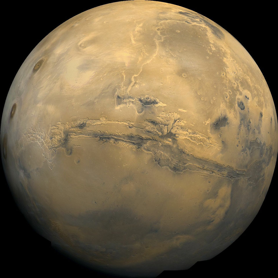 Der Mars füllt die Bildfläche bis zum Rand. In der Mitte verläuft das breite und tiefe Valles Marineris, eine lange und breite Schlucht.