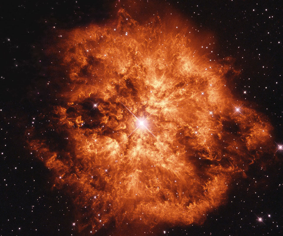 Um den Wolf-Rayet-Stern WR 124 leuchtet ein stark strukturierter orangefarbener Nebel.