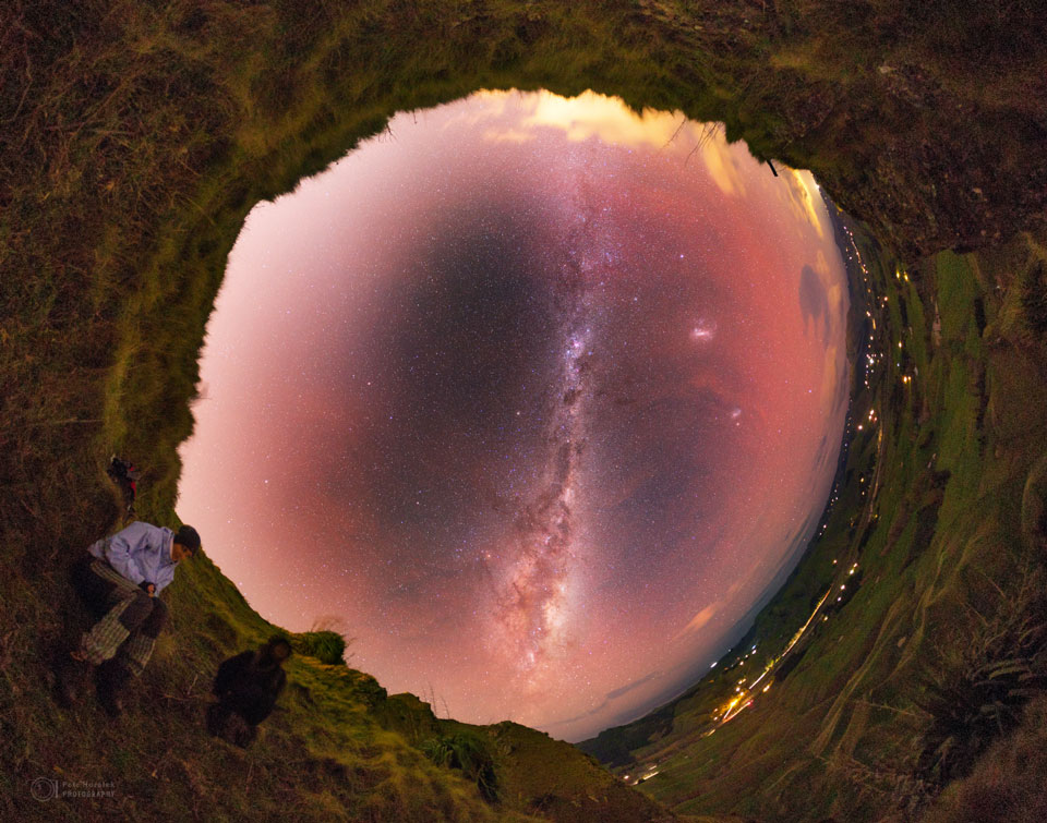 Der Himmel ist auf diesem Panoramabild eine große, rot leuchtende Öffnung. Außen herum verläuft eine Graslandschaft. Das Panorama ist eine Kleiner-Planet-Projektion mit Blick zum Himmel.