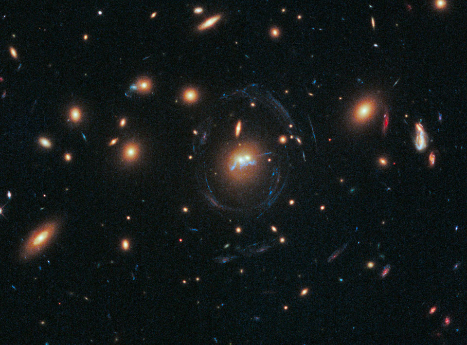 Der Haufen SDSS J1531+3414 im Sternbild Nördliche Krone enthält viele gelbe elliptische Galaxien. Sie sind im Bild verteilt. Das Zentrum ist von blauen dünnen Fasern umgeben. Über das Zentrum verläuft eine blaue verschnörkelte Brücke.
