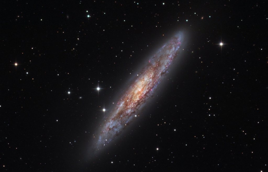 In kleinen Teleskopen wirkt NGC 253 im Sternbild Bildhauer wie eine Münze. Sie heißt daher Silberdollargalaxie. Hier schwebt sie schräg zwischen wenigen Sternen.