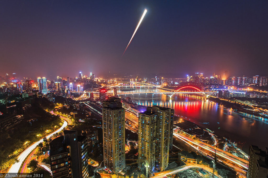 Über den bunten Stadtlichtern der chinesischen Stadt Chongqing steigt der verfinsterte Vollmond nach Sonnenuntergang auf.