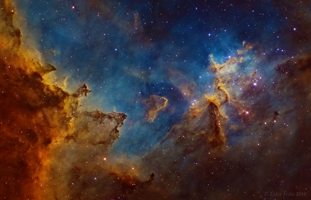 Unten ist ein orange-braunes Nebelgebirge, oben leuchten blaue Gaswolken, die von Sternen gesprenkelt sind.
