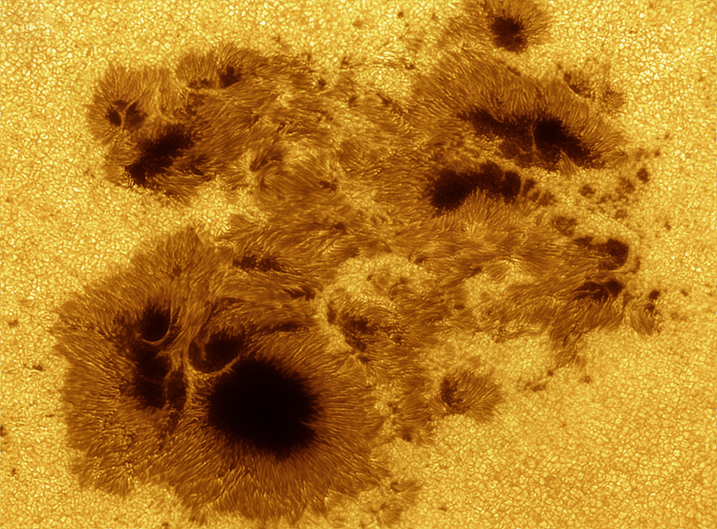 Eine gewaltige Sonnenfleckengruppe mit Umbrae und Penumbrae füllt das Bild. Außen herum sind Granulen auf der Sonnenoberfläche.