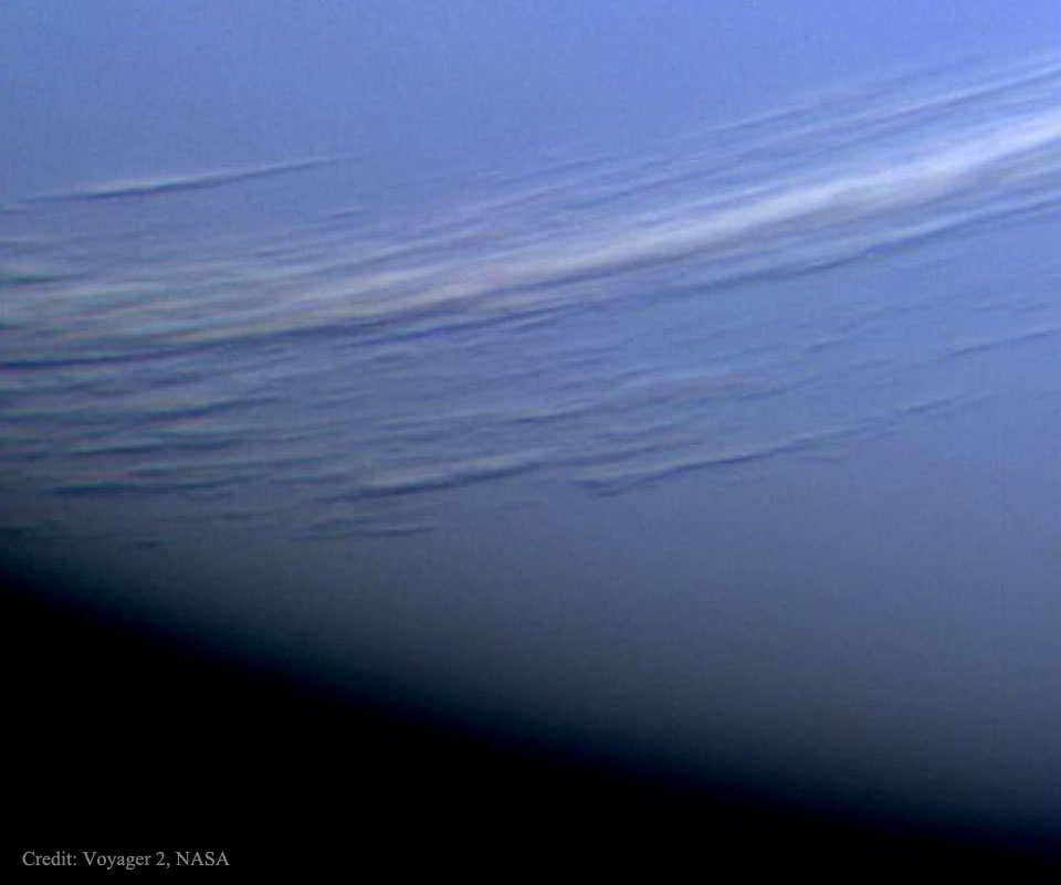 Über der blauen Oberfläche von Neptun schweben weiße Wolken, die Schatten auf die tiefer liegenden blauen Wolken werfen. Das Bild stammt von der Raumsonde Voyager 2.