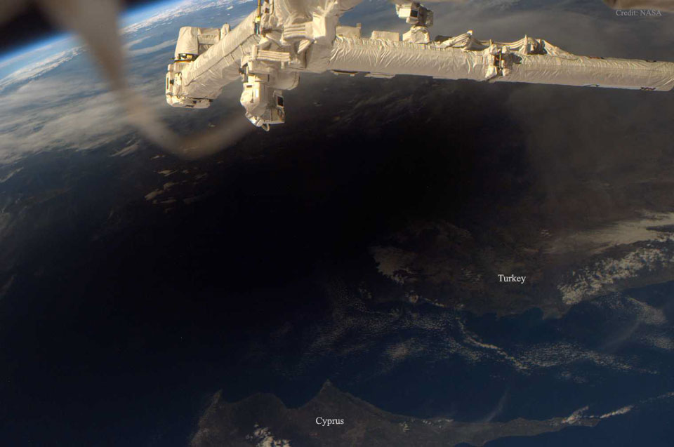 Hinter dem Canadarm2 der Internationalen Raumstation fällt der Schatten des Mondes auf die Erde. Die Menschen im Schatten sahen eine Sonnenfinsternis.