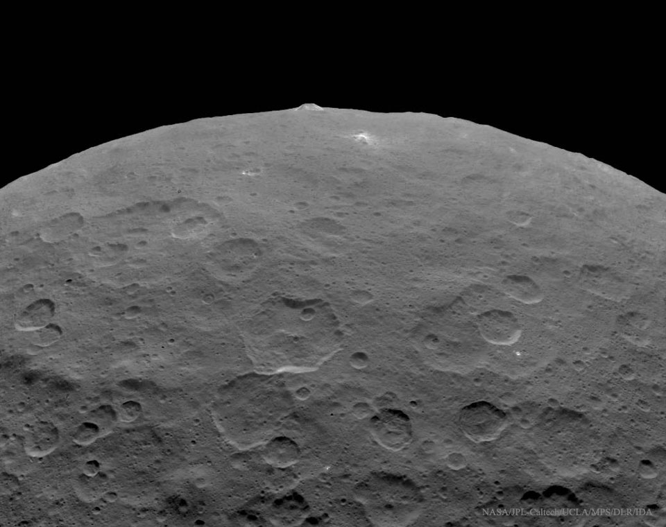 Das Bild zeigt einen Teil des Asteroiden Ceres, der Rand des Zwergplaneten ist oben. Am Rand ragt ein Berg auf. Rechts darunter ist einer der rätselhaften hellen Flecken zu sehen.