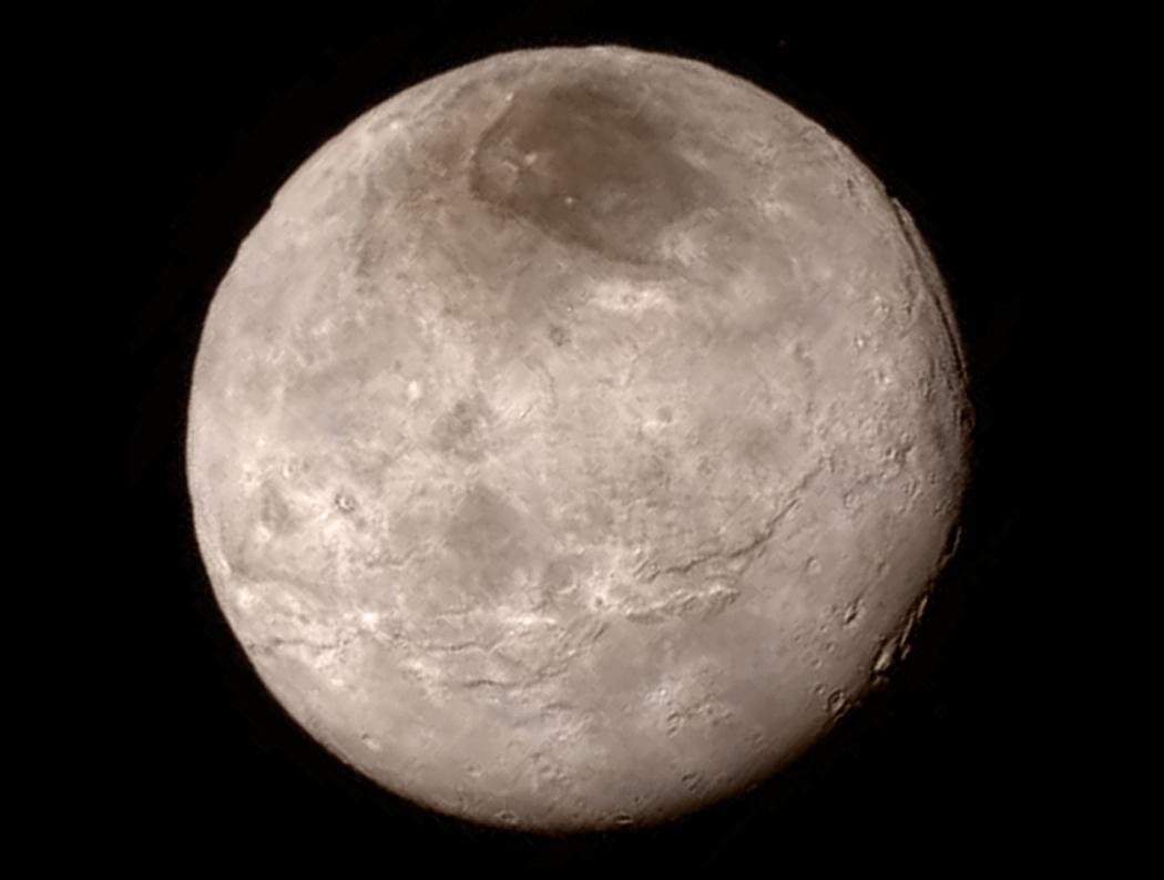 Der Plutomond Charon wirkt fremdartig. Oben ist eine dunkle Region, vorne verläuft eine tiefe Schlucht, und am Rand schneidet eine tiefe Schneise durch die Oberfläche.