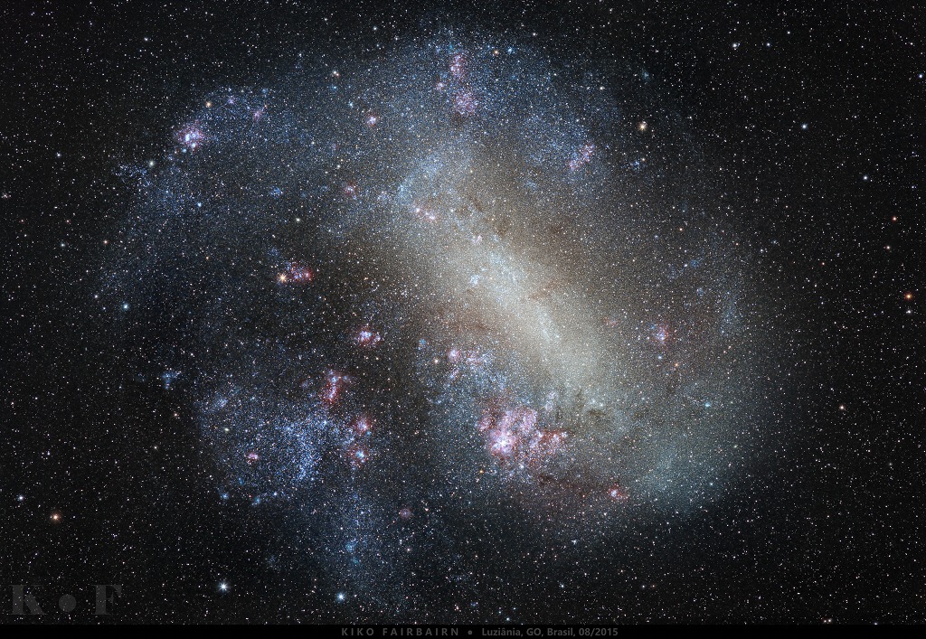 Die Große Magellansche Wolke im Bild besitzt einen Balken, der hier diagonal durchs Bild verläuft. Sie wirkt unregelmäßig und ist von rosaroten Sternbildungsregionen gesprenkelt.