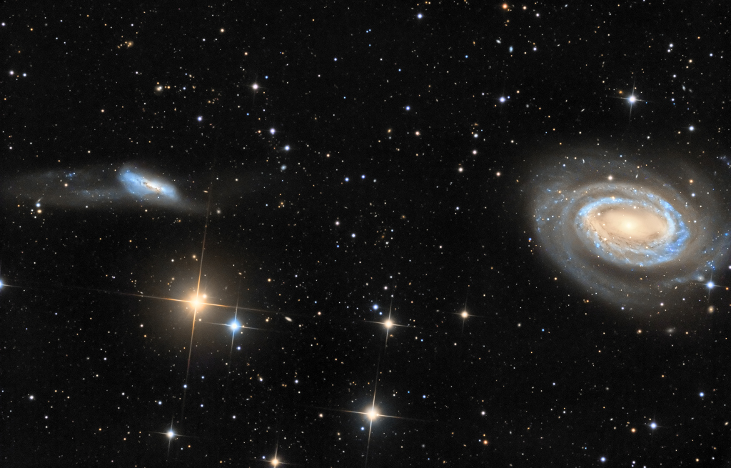 Rechts am Rand ist eine prachtvolle Spiralgalaxie mit nur einem markanten Spiralarm. Links ist eine fluffige Galaxie mit Gezeitenschweifen.