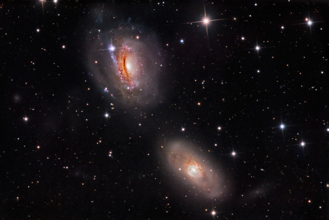 Zwei Spiralgalaxien sind übereinander angeordnet. Wir sehen sie schräg von oben. Auf den ersten Blick wirken sie normal, auf den zweiten Blick erkennt man, dass sie durch die Gezeiten verzerrt sind.