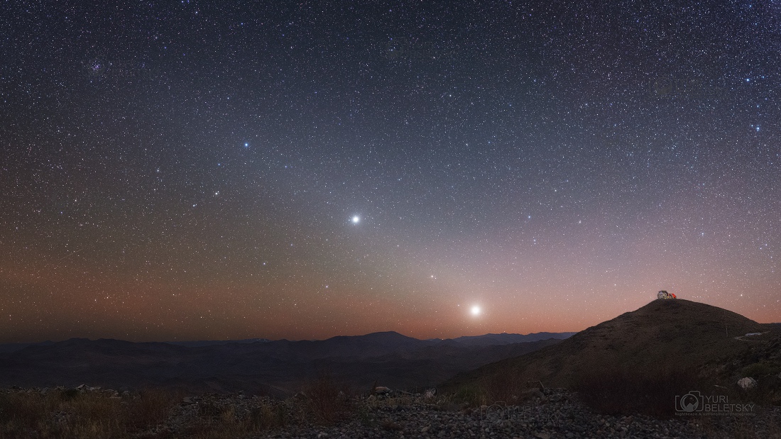 Das Bild zeigt Planeten in der Ebene der Ekliptik. Am Horizont ragt ein Berg mit einem Observatorium hoch.