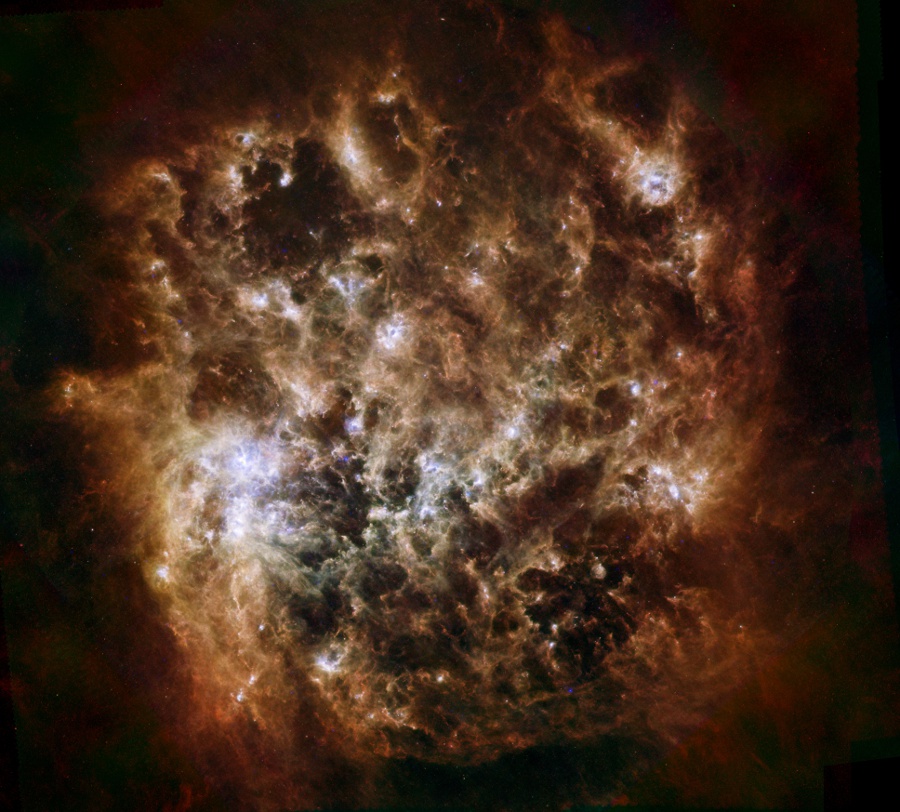 Das Infrarotbild des Weltraumteleskops Herschel zeigt die Große Magellansche Wolke als turbulente Staubwolke mit einigenhell leuchtenden Stellen.