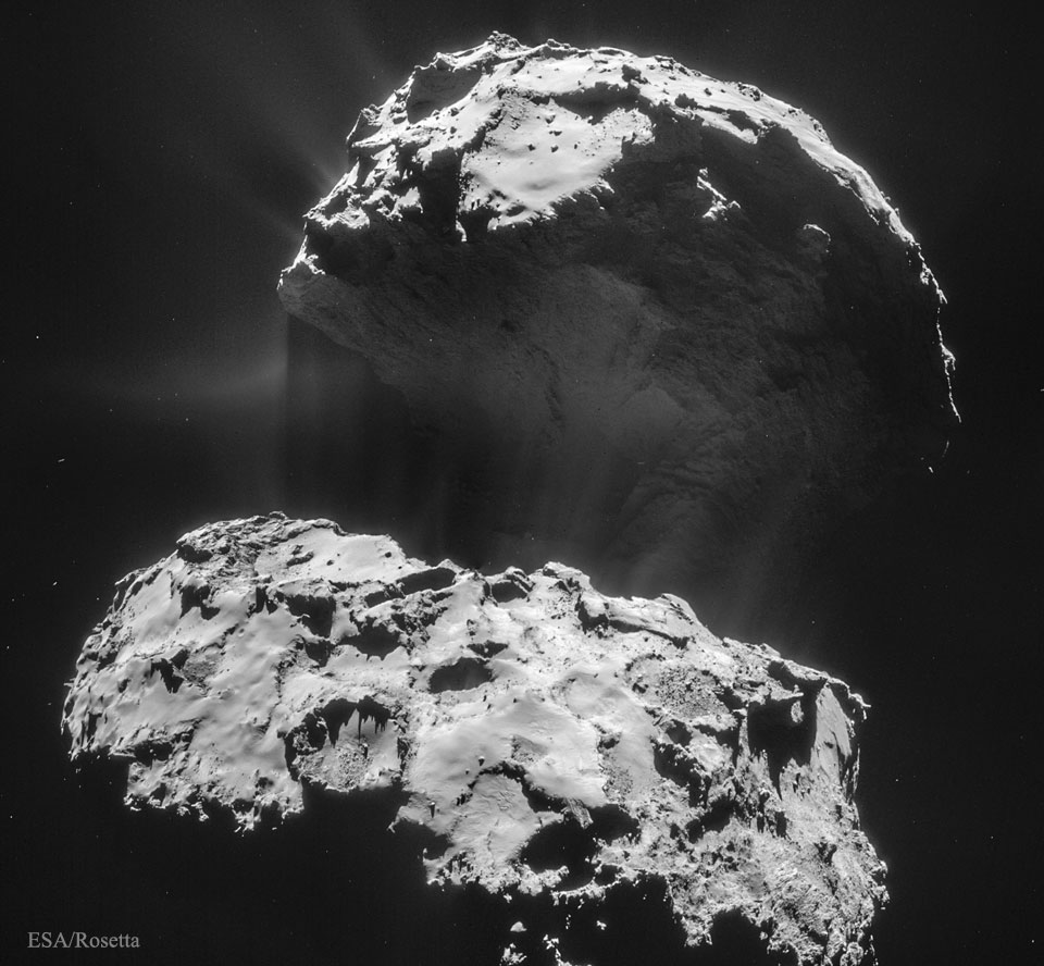 Der Kern des Kometen 67P/Tschurjumow-Gerassimenko ist schwarz wie Kohle. Er ist bildfüllend dargestellt, seine Lappen und der dünne Steg sind gut erkennbar. Außen strömen Strahlen aus Gas und Staub von der Oberfläche weg.