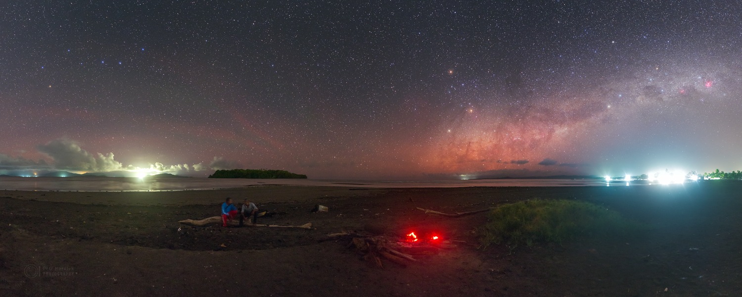 Am Strand leuchtet noch die Glut eines Feuers. Darüber bilden Mars, Saturn und Antares ein Dreieck. Links zeigt der Große Wagen zum Nordstern, rechts das Kreuz des Südens zum Himmelsnordpol.