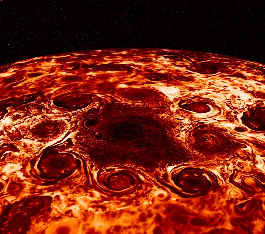 Jupiters Nordpol ist in Infrarotlicht abgebildet. Um einen dunklen Bereich sind mehrere dunkle Wirbel angeordnet.