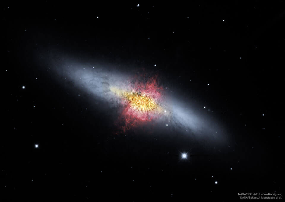 Das Bild zeigt die Galaxie M82. Die irreguläre Galaxie liegt schräg im Bild, in der Mitte sind stark strukturierte gelbe und rötliche Nebel, nach links und rechts breitet sich weißer Nebel aus.