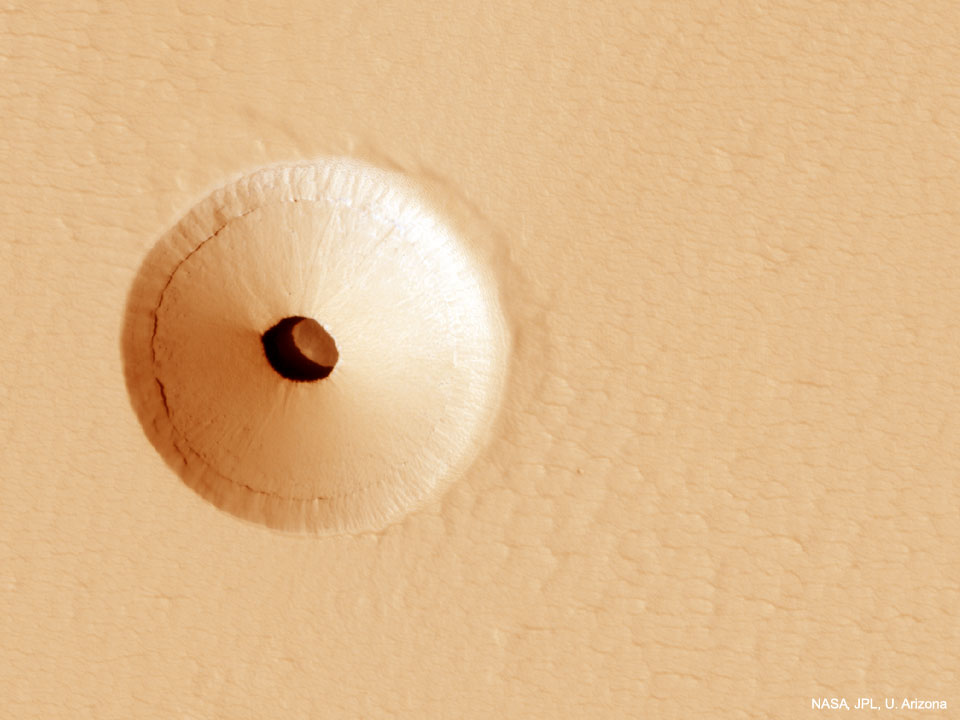 Ein Loch im Mars ist von einem Krater umgeben. Der Boden ist teilweise beleuchtet. Möglicherweise liegt darunter eine größere Höhle.