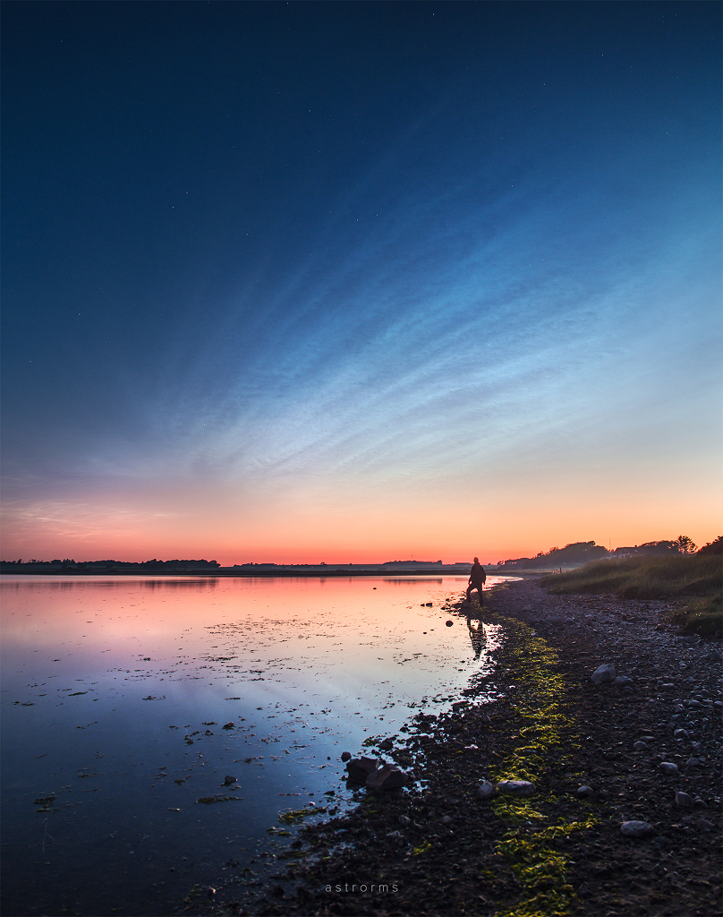 Leuchtende Nachtwolken, die auch als polare Mesosphärenwolken bezeichnet werden, spiegeln sich im Wasser bei Nykøbing Mors in Dänemark.