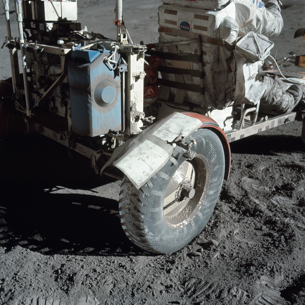 Rad und Kotflügel des verstaubten Rover von Apollo 17 nach der Montage einer Reservekarte mithilfe von Klammern und einem grauen Streifen Klebeband.