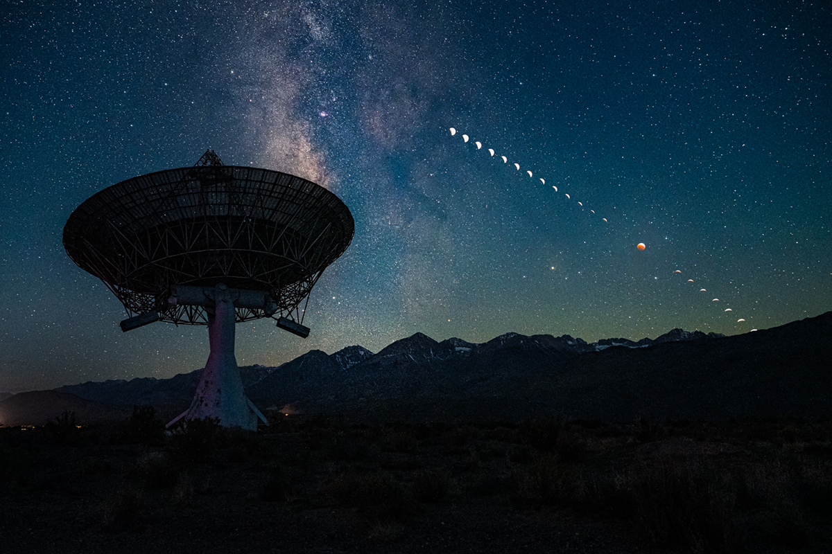 Hinter einer Radioteleskopschüssel des kalifornischen Owen's Valley Radio Observatory sinkt der Mond während einer totalen Mondfinsternis zu den zerklüfteten Bergen der Sierra Nevada hinunter.
