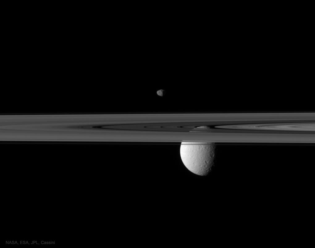 Die Raumsonde Cassini fotografierte die Saturnmonde Janus und Rhea hinter den Ringen.