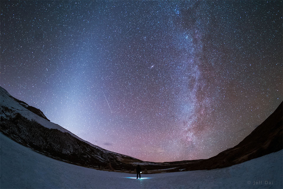 Dieses Bild zeigt eine Nachtlandschaft über China mit Bändern aus Zodiakallicht links und dem zentralen Band unserer Milchstraße rechts.