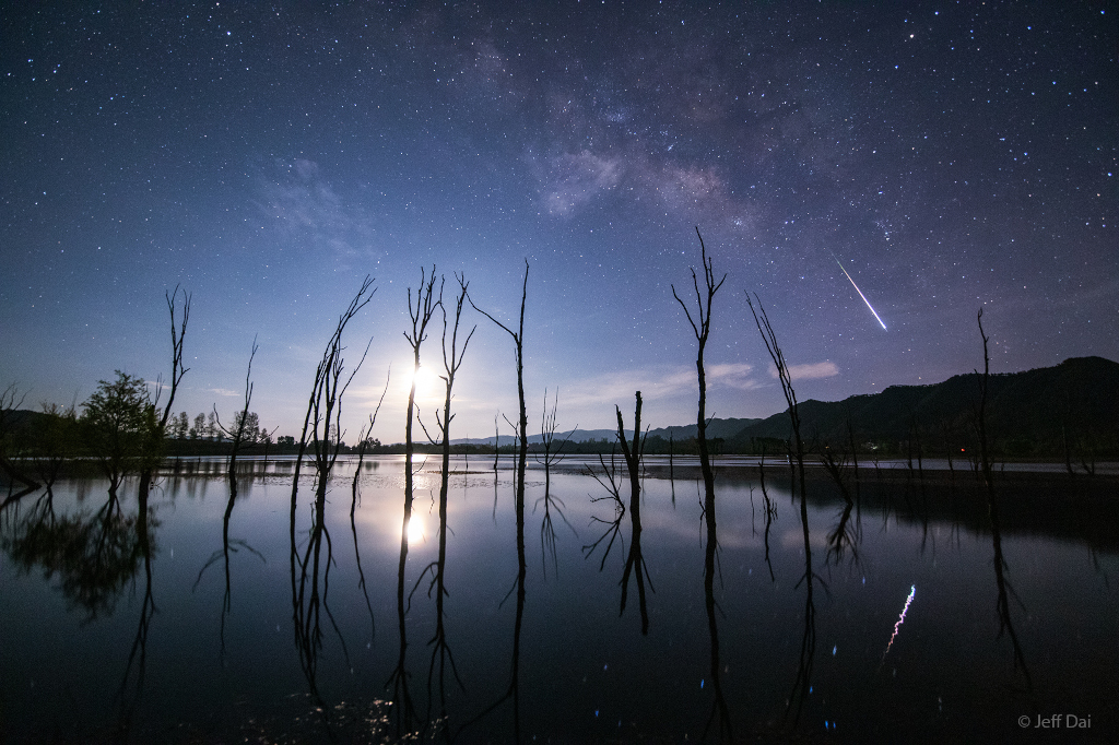 Ein Meteor des Lyriden-Meteorstroms und der abnehmende Mond werfen ihr Licht auf den See Nian in der chinesischen Provinz Yunnan.